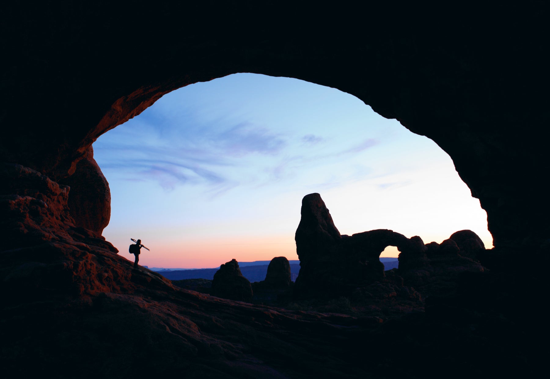 Silhouetted portrait of Peter Lik hiking through Arches National Park in Utah set to a backdrop of arches, balanced rocks and slabs of slickrock