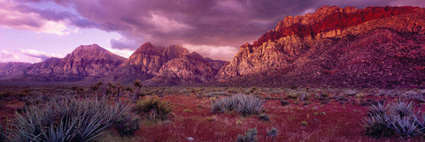 Brush filled desert below the cloud covered sandstone peaks of Red Rock Canyon Nevada 