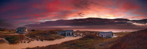 Three shacks spread out along the grass brush and sand beaches of Cape Cod Massachusetts at sunset