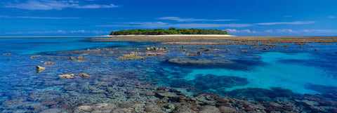 Reef and Turquoise ocean in front of a tree filled island in the Great Barrier Reef