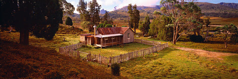 Old wooden shack with a picket fence surrounded by trees in Tasmania, Australia