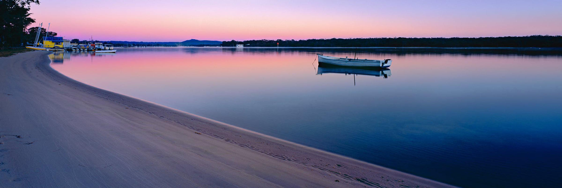 Rowboat floating and reflecting off the water near the banks of the Noosa River at sunrise