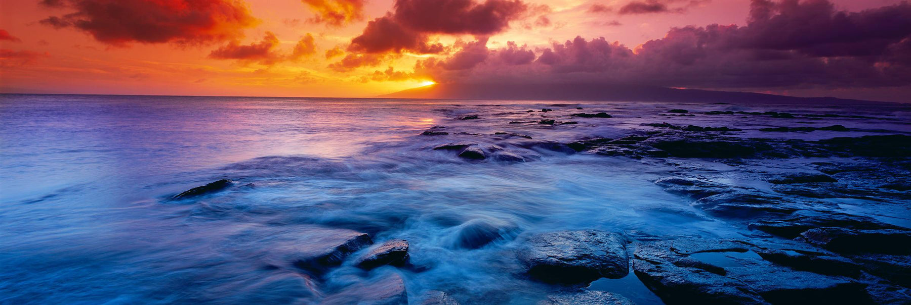 Waves washing over the black rock coast of Kapalua Bay Hawaii at sunset