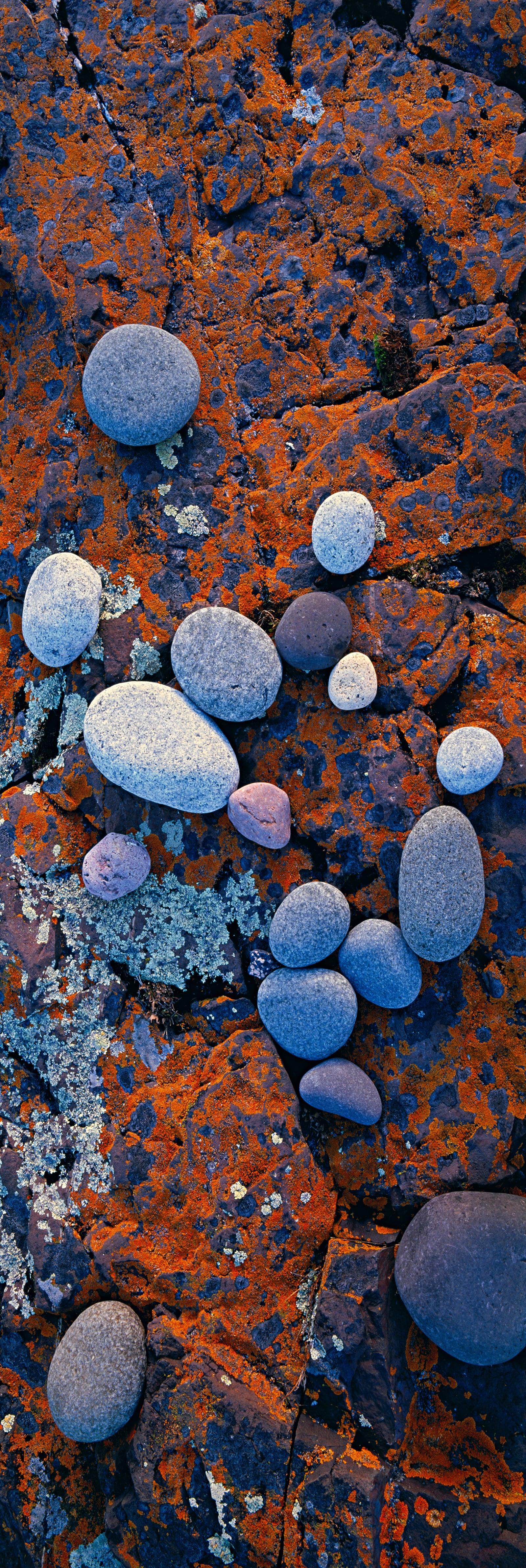 Collection of colored rocks sitting on the red moss covered stone of Split Rock Lighthouse State Park Minnesota