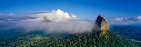 Mountain peaks covered by rolling clouds in the tree covered plains of Glass House Mountains National Park Australia