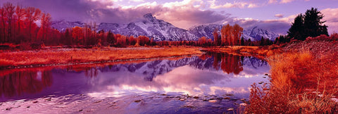 Snow covered Grand Teton Mountains and orange foliage reflecting into the Snake River at sunset