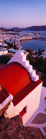 Red and white rooftop of a church overlooking the city of Mykonos Greece and its bay full of boats