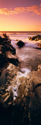 Ocean waves washing over the rocky tidal pools in Hana Hawaii at sunset