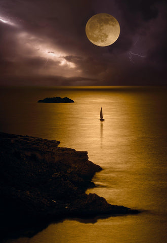 Sail boat off the rocky coast under a full moon and lightning filled sky at night