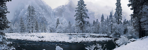 River running through the snow covered forest of Yosemite National Park California with a waterfall in the background 