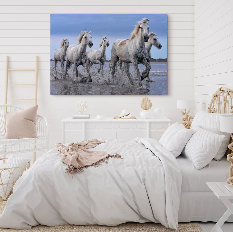 Large photo of white horses running in water on the beach by Peter Lik hanging on white walls of a country bedroom