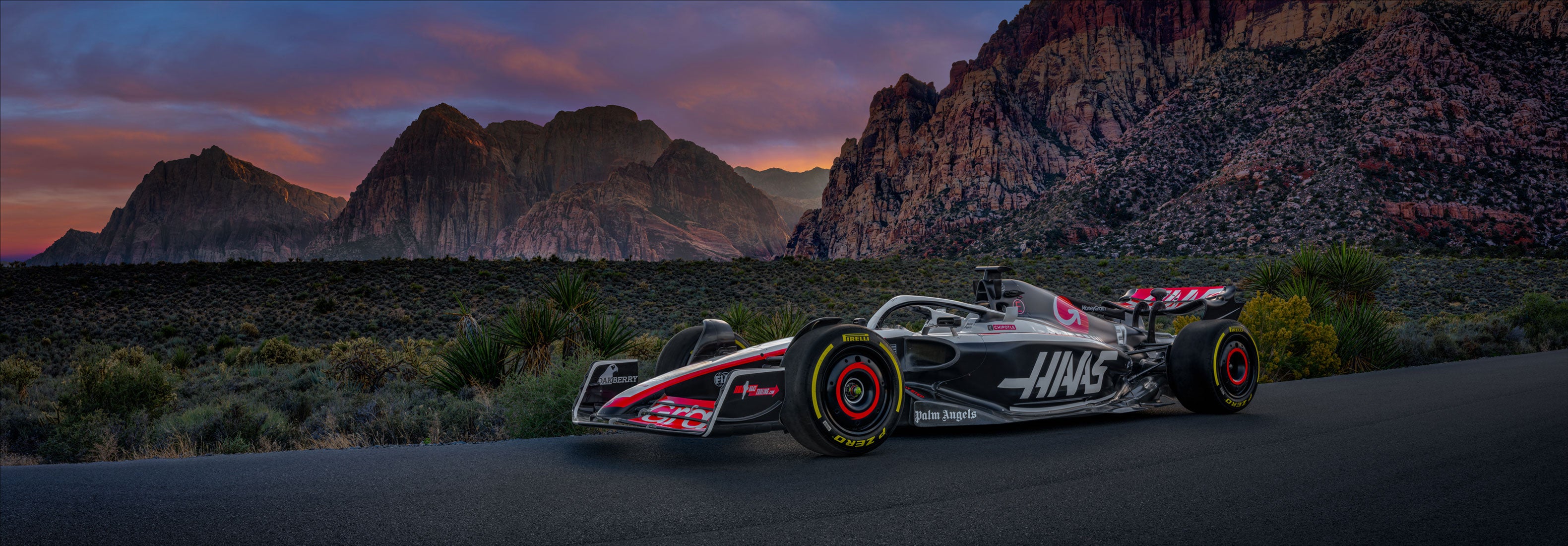 Photo of the Haas race car on the road in front of Red Rock Canyon, Las Vegas at sunset.