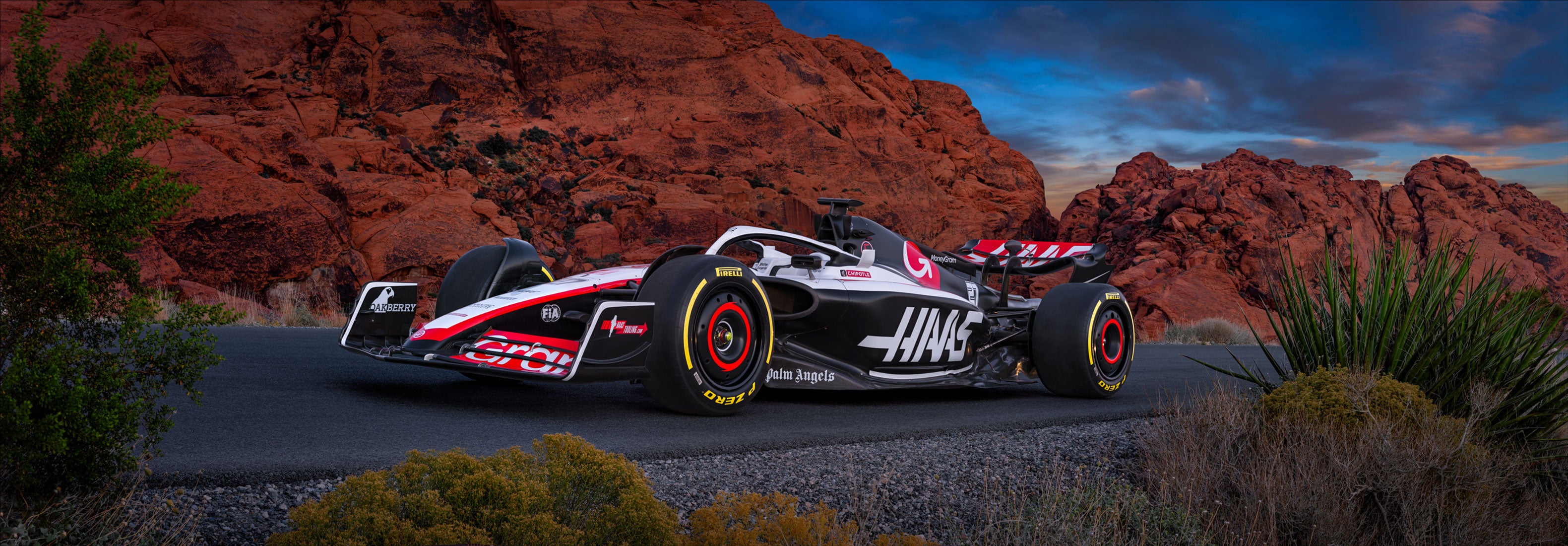 Photo of the Haas F1 race car on the road in front of the cliffs of Red Rock Canyon, Las Vegas just before sunset.