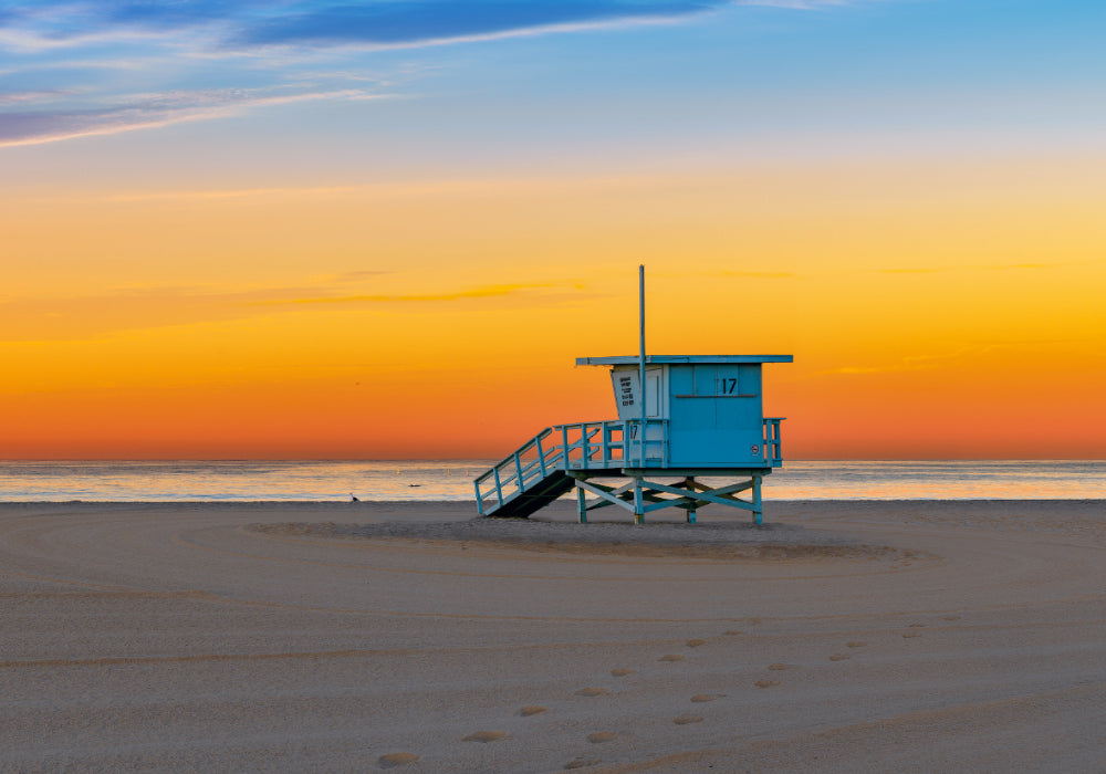 Blue life guard shack on the sandy beach of Santa Monica California at sunset