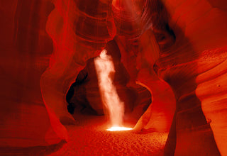 Sun shining into dust in the shape of a ghost within the sandstone walls of the slot canyons in Antelope Canyon Arizona