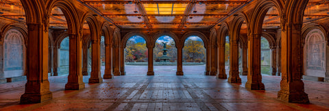 Captivating golden glow of Bethesda Terrace in Central Park, with arches framing Bethesda Fountain and autumn leaves on a serene morning.