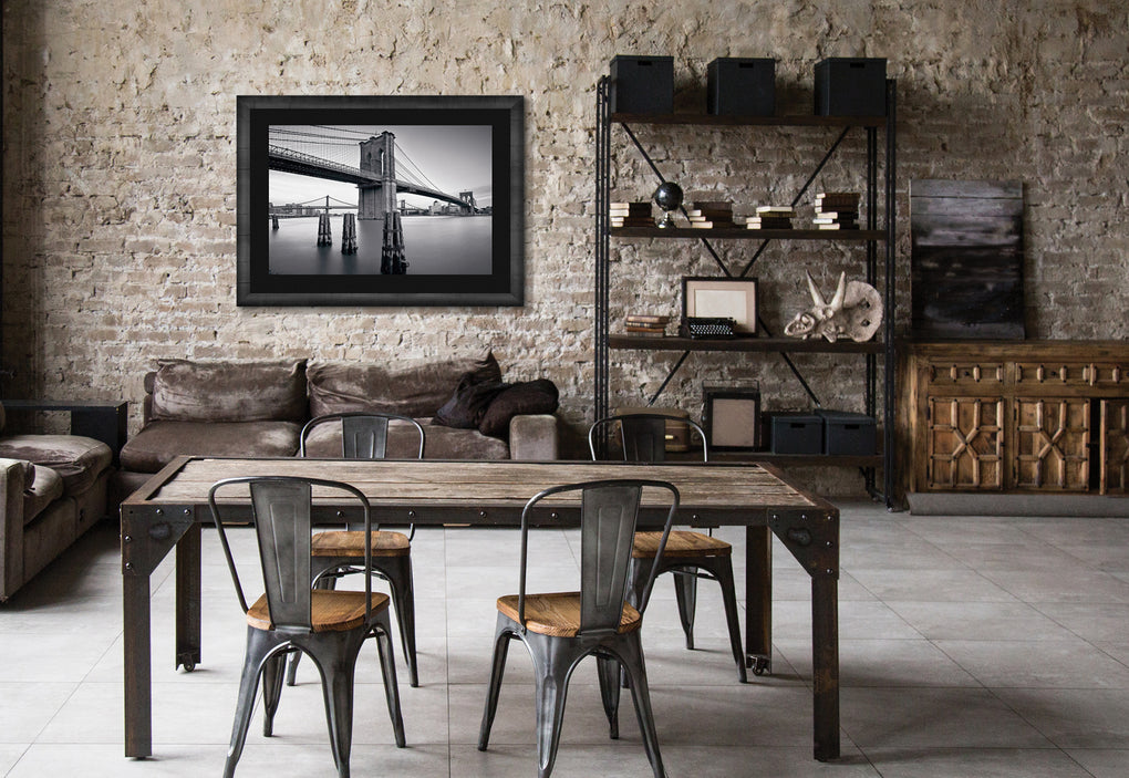 New York loft with aged brick walls, industrial furniture and a framed black and white photograph of Manhattan Bridge