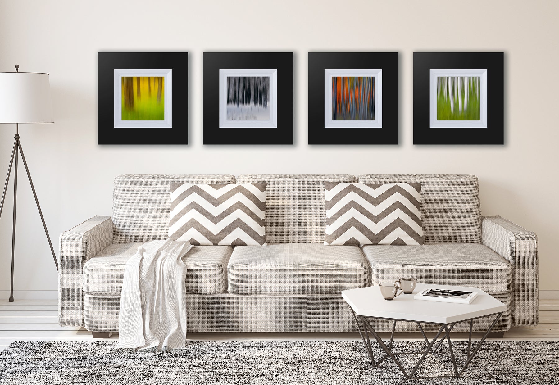Living room with gray couch and white table featuring four framed square photographs of blurred Aspen trees by Peter Lik in dark brown frames with white linen liners