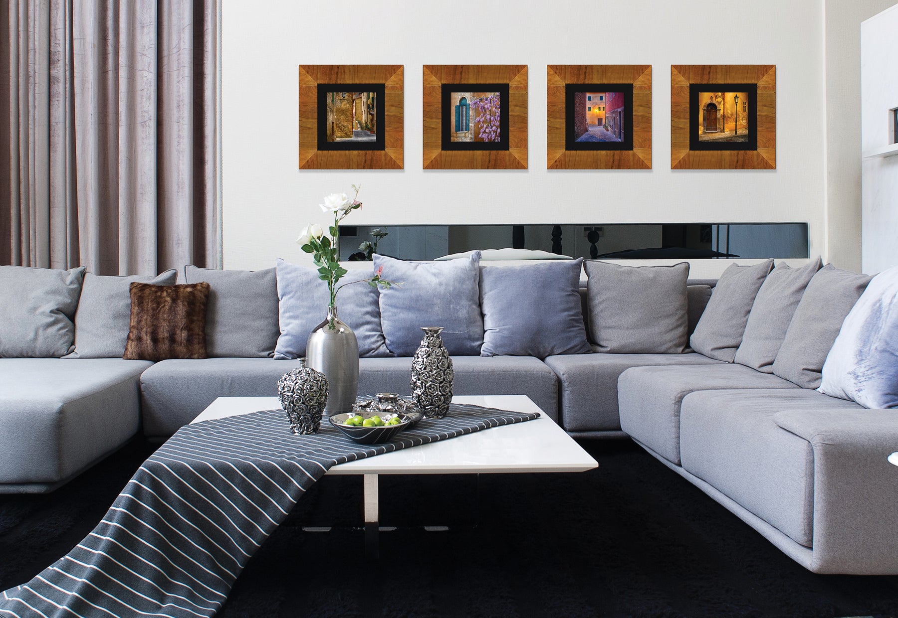 Modern living room with gray couch and white table featuring four framed square photographs of Italy by Peter Lik in light brown frames with black linen liners