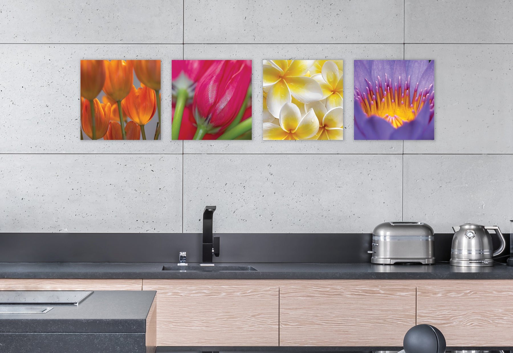 Sleek modern kitchen with light brown cabinets, dark gray countertops and concrete walls featuring four square photographs of colorful flowers by Peter Lik