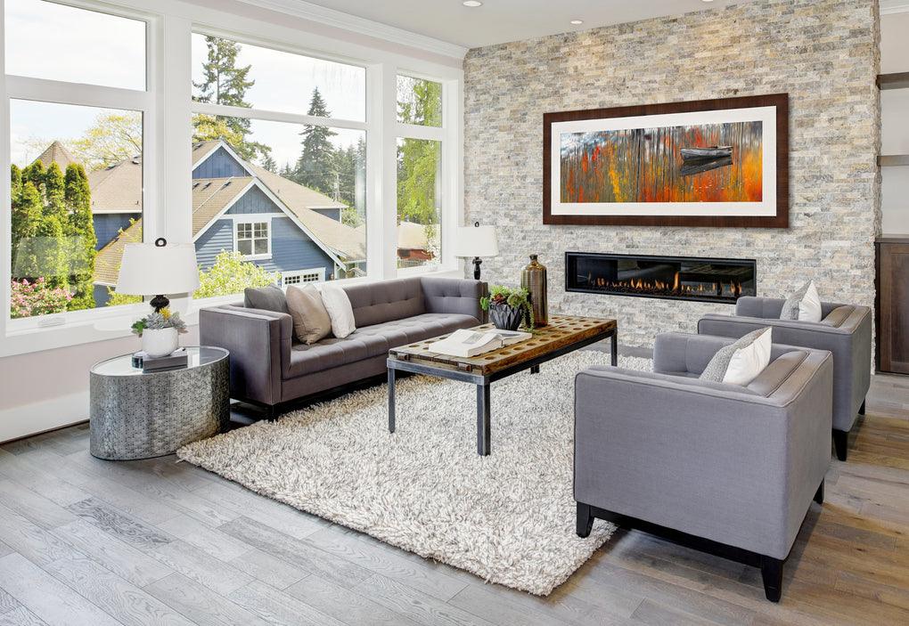 Modern living room with light gray fireplace featuring a framed photograph by Peter Lik of a rowboat on a lake in Aspen 
