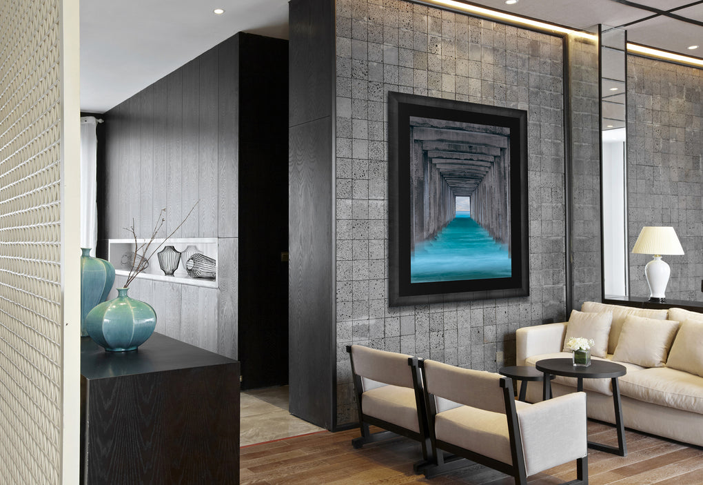 Office lobby with white chairs and a gray stone featuring a photograph of Scripps Pier from below in Pacific blue water