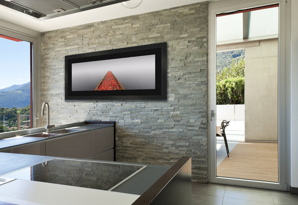 Modern kitchen with gray stone wall featuring a framed photograph of a pier covered in orange leaves during a misty morning