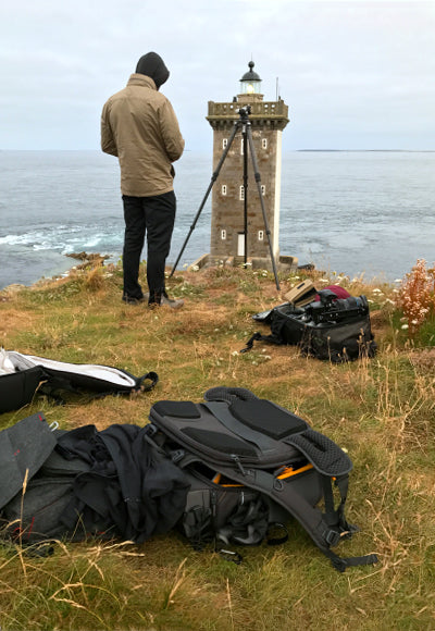 Portrait of Peter Lik setting up to photograph a lighthouse under overcast skies in the Brittany Region of Northwest France