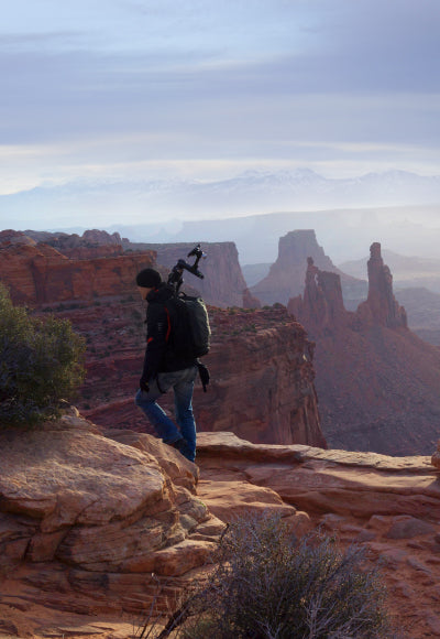 Portrait of Peter hiking though Canyonlands National Park in Utah with a tripod over his shoulder