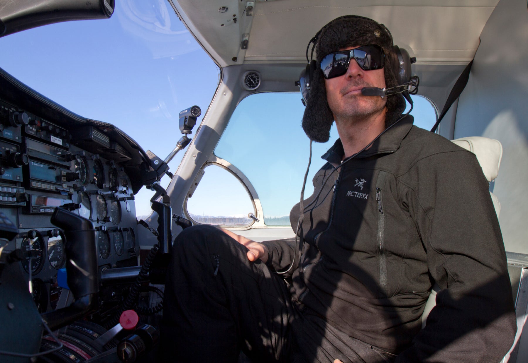 Portrait of Peter Lik sitting in a helicopter in Alaska wearing sunglasses flight communication headgear