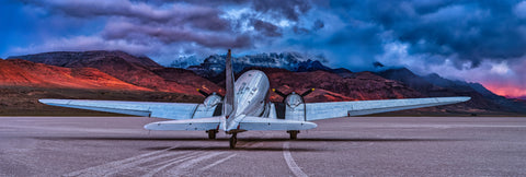 The Art of Flight by Peter Lik, a Douglas DC-3 on the Alvord Desert lakebed in Oregon beneath storm clouds and sunrise-lit mountains, acrylic recess mount