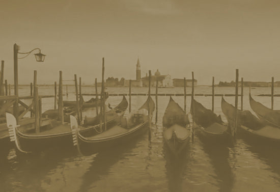 A row of gondolas tied to poles in the canals of Venice, Italy.