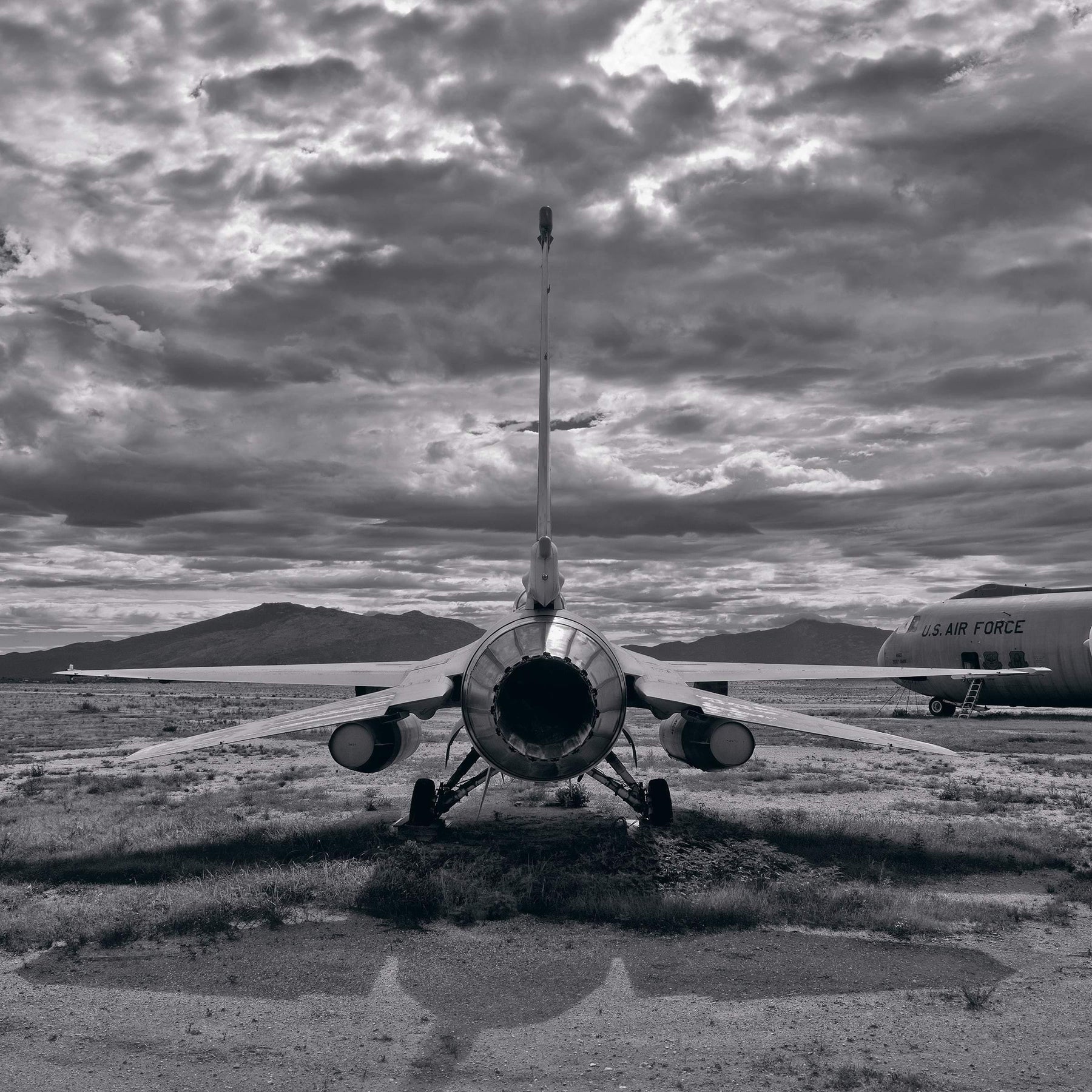 Black and white back view of an old F-16 on a grass and dirt field in Tucson Arizona