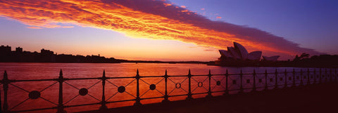 Rod iron fence at the edge of Sydney Harbor during the sunset glow with Sydney Opera House in the background