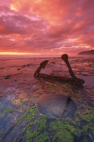 Rusty old anchor on its side in the shallow tide pools off the coast of the Great Ocean Road Australia