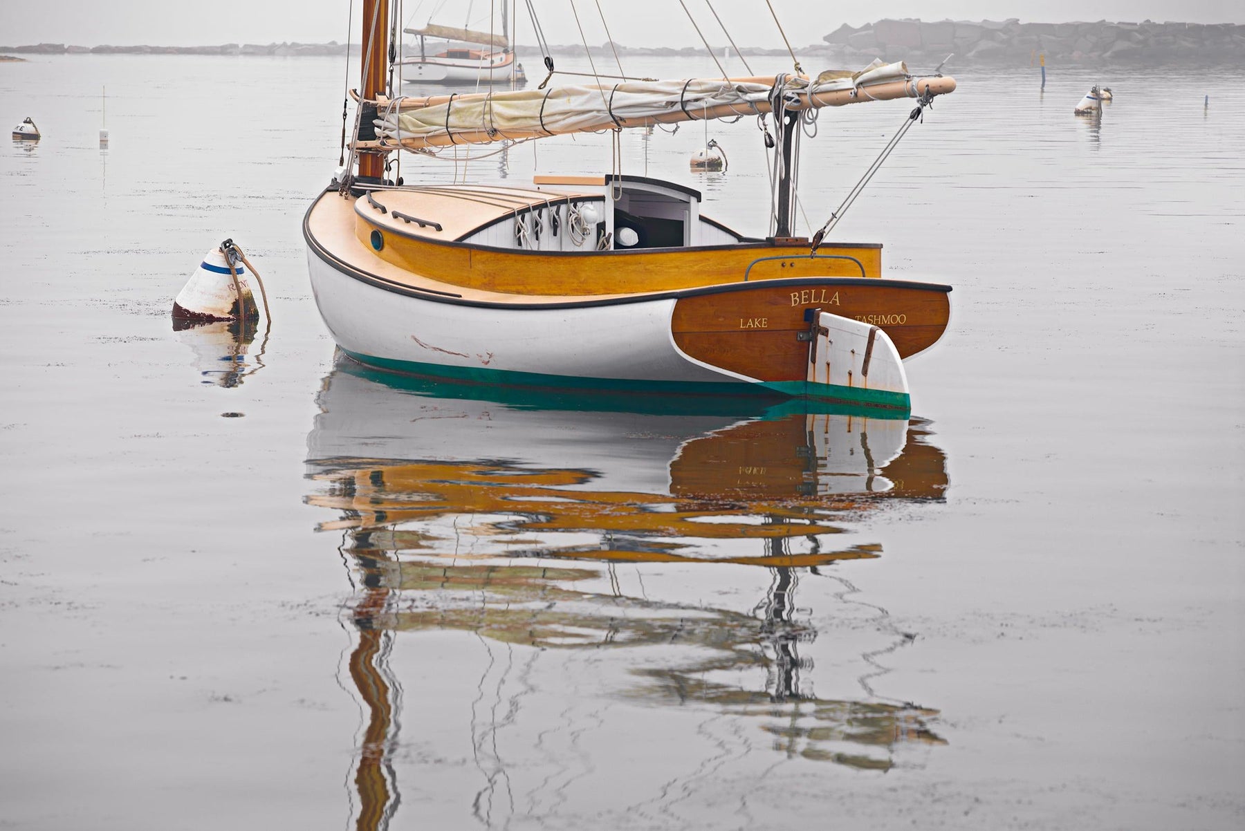 Sail boat and buoy reflecting off the water in a fog filled harbor in Martha's Vineyard Massachusetts