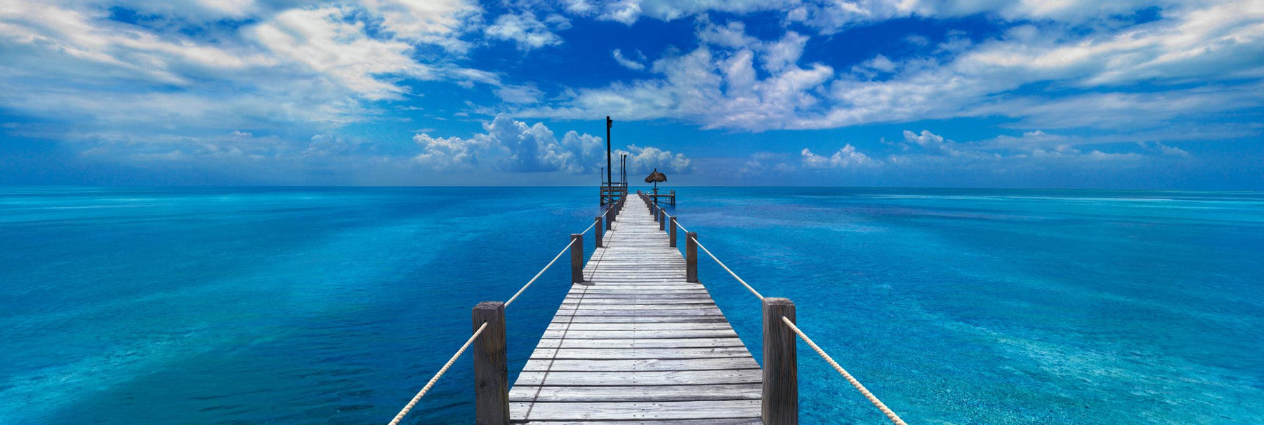 White washed wooden Jetty with rope handrails reaching out over the turquoise ocean in Key West Florida