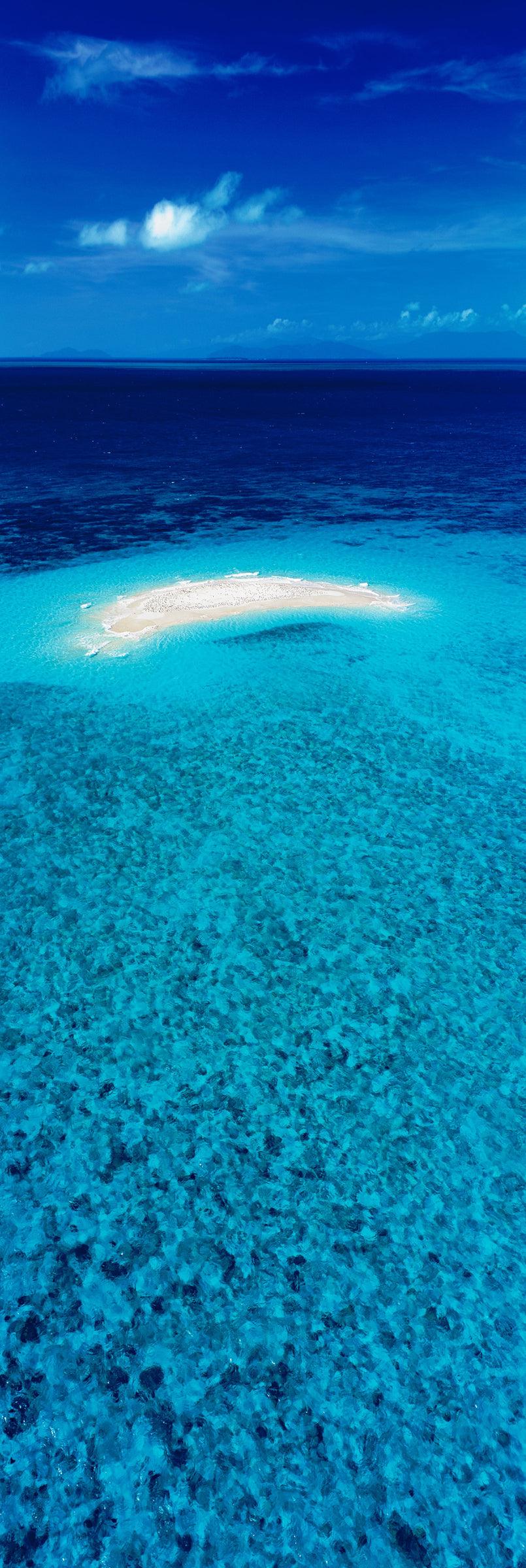 Aerial view of the blue ocean and a small white sand island in off the Great Barrier Reef Australia