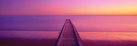 Timber Jetty stretching out into the ocean at Hervey Bay Australia during a pink sunrise