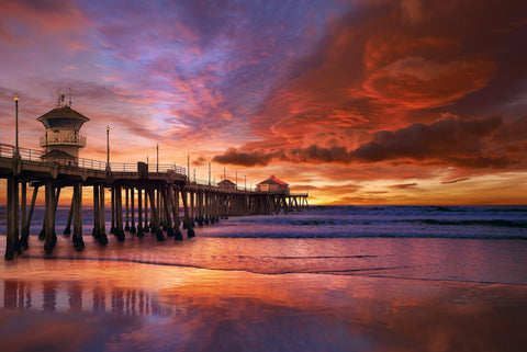 Huntington Beach Pier leading over the ocean under a red cloudy sky at sunset 