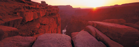 Edge of a rock cliff looking down at the Colorado River at the bottom of the Grand Canyon Arizona at sunrise