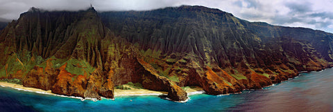 Aerial view of the grass covered cliff shoreline of Na Pali Coast Hawaii dropping into the ocean