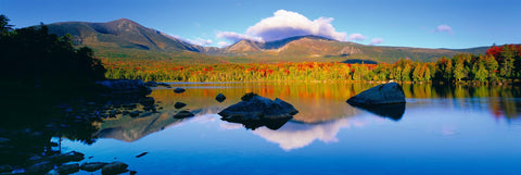 Large rocks near the shore of a lake surrounded by the Autumn colored forest and mountains of Baxter State Park Maine