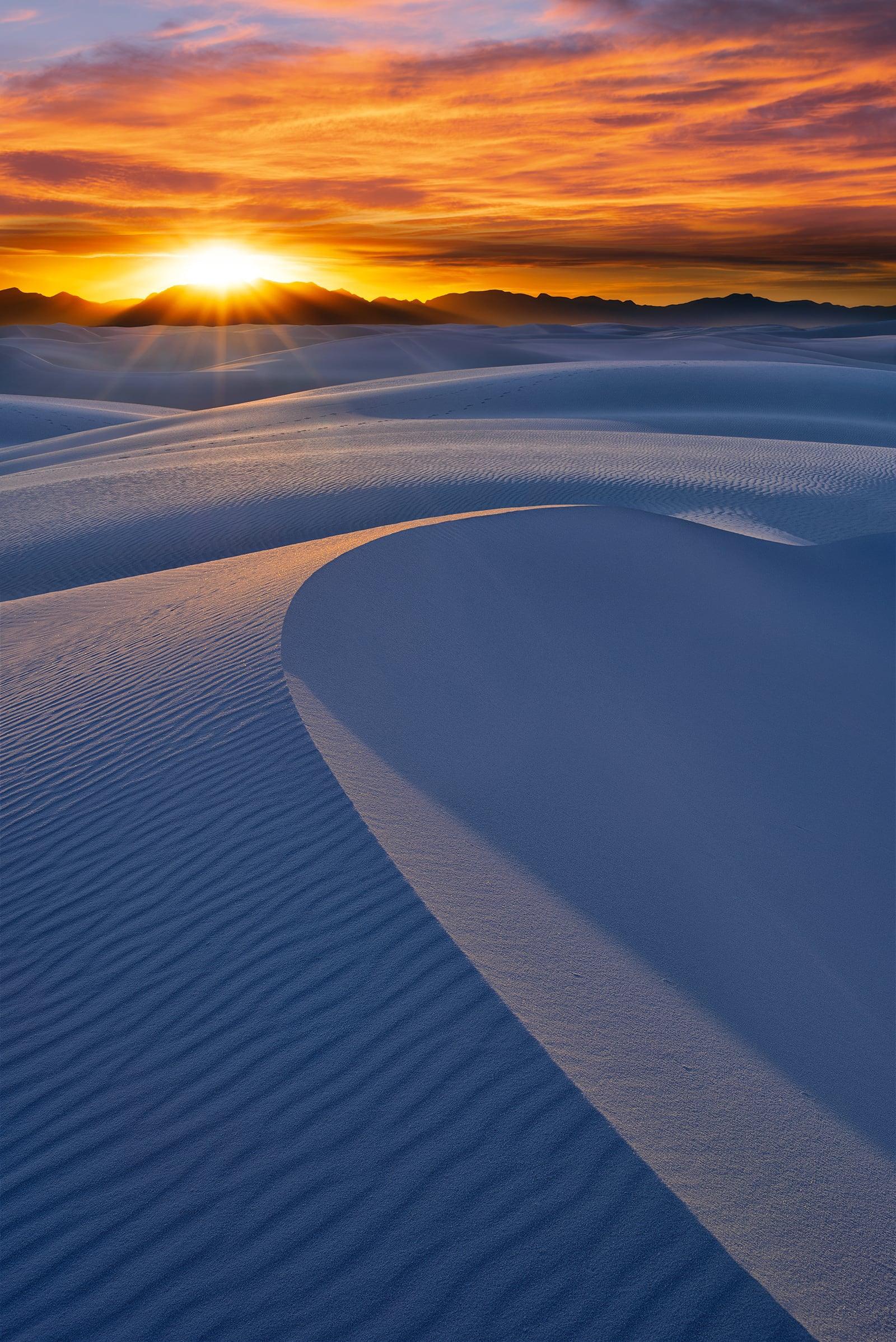 Sun setting behind the hills and windswept sand dunes at White Sands National Monument New Mexico