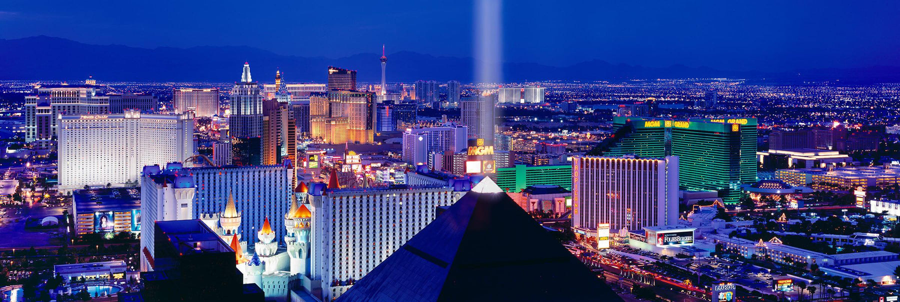 Rooftop view of the Las Vegas Strip and the Luxor pyramid shining into the sky at night