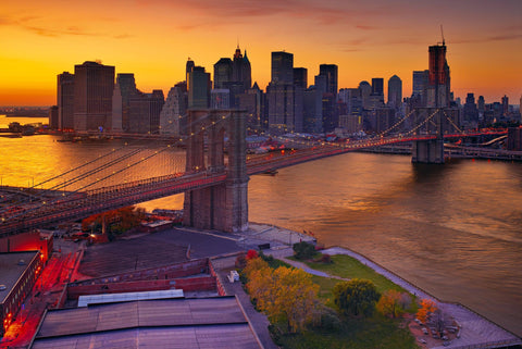 Rooftop view of the Brooklyn Bridge at sunset leading over the East River into Brooklyn New York