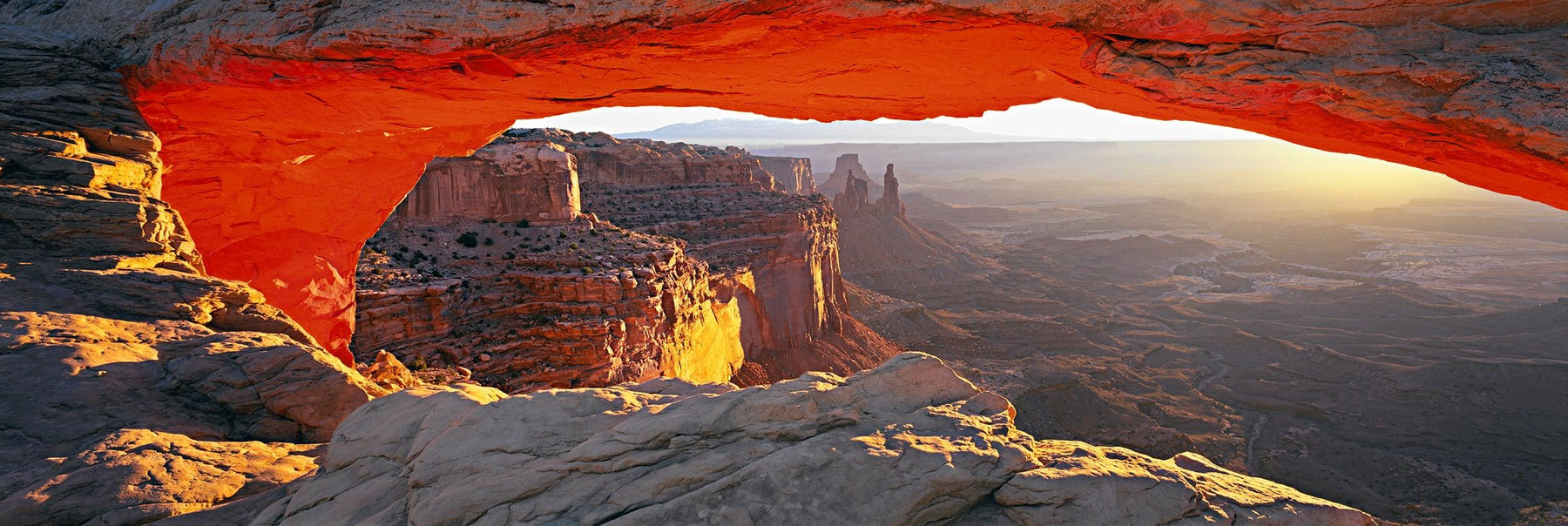 Sun shining through the rock arch that overlooks the valley of Canyonlands National Park Utah 