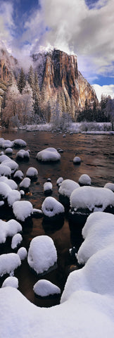 Snow covered rocks on the edge of the river running through Yosemite Valley with El Capitan mountain in the background