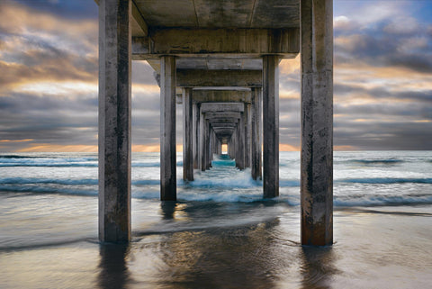 Waves crashing under the pier and onto the beach in La Jolla California on a stormy day