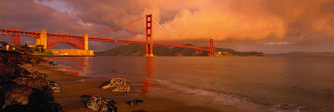 Rock and sand beach looking back at the Golden Gate Bridge during a cloud filled sunset